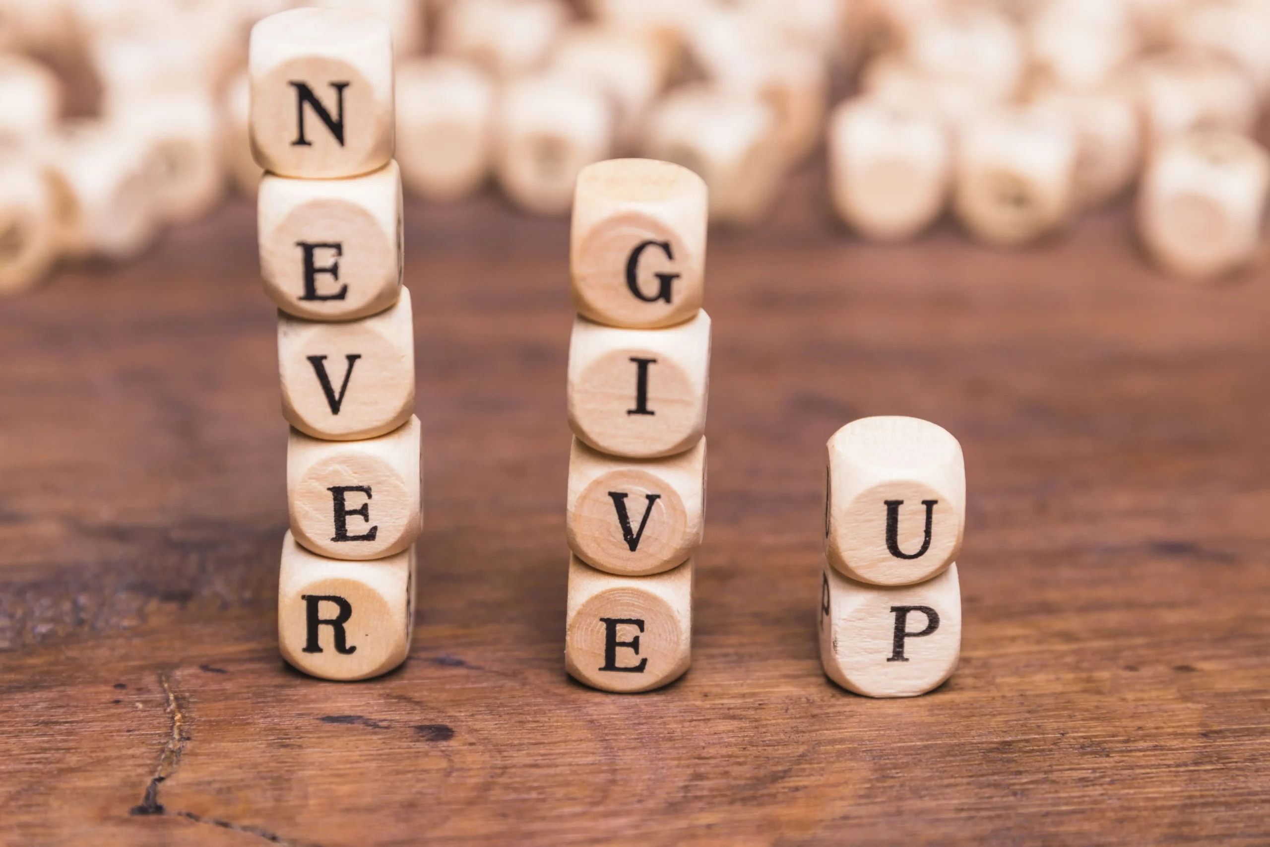 stacked-wooden-blocks-with-word-never-give-up-wooden-desk-min