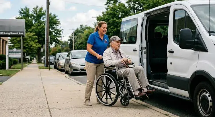 Caregiver helping a senior board a wheelchair-accessible van, illustrating how much does a medical transport cost per hour for non-emergency wheelchair transportation.
